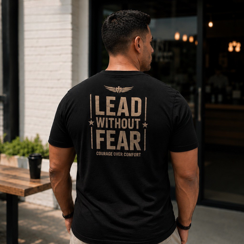 A man viewed from behind wearing a black t-shirt with a large beige graphic on the back that reads 'LEAD WITHOUT FEAR' and 'COURAGE OVER COMFORT'.