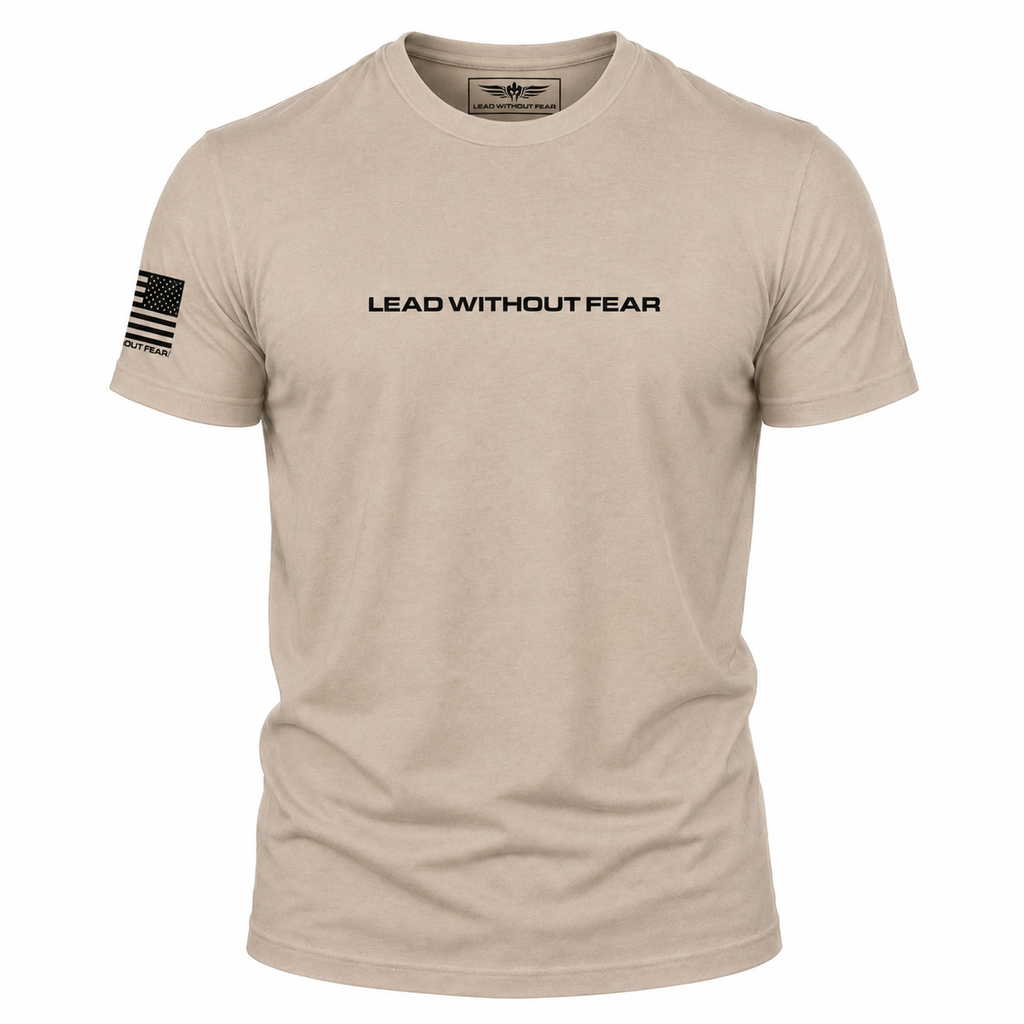 A light tan crewneck t-shirt with 'LEAD WITHOUT FEAR' printed in black across the chest and a black American flag graphic on the right sleeve, shown on a plain white background.