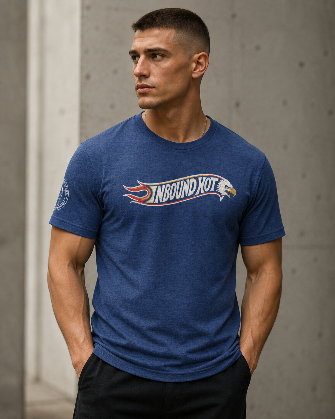 A man wearing a heather blue crewneck t-shirt with a 'NBOUND HOT' graphic across the chest, standing against a concrete wall.