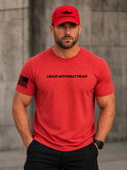 A man wearing a red crewneck t-shirt with 'LEAD WITHOUT FEAR' printed across the chest and a black American flag graphic on the sleeve, paired with a matching red baseball cap.
