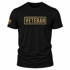 A black short-sleeve crewneck t-shirt featuring a distressed gold rectangular 'VETERAN' box logo on the chest and a small tan American flag graphic on the right sleeve, shown against a plain white background.