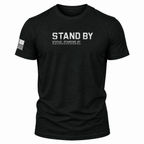 A black short-sleeve t-shirt with 'STAND BY' printed in distressed white letters on the chest, with 'STATUS: STANDING BY' underneath. A distressed black-and-white American flag is printed on the right sleeve.