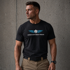 A muscular man wearing a black crewneck t-shirt with a blue and white winged logo and the text 'LEAD WITHOUT FEAR' on the chest, paired with khaki pants, standing against a textured gray concrete wall.